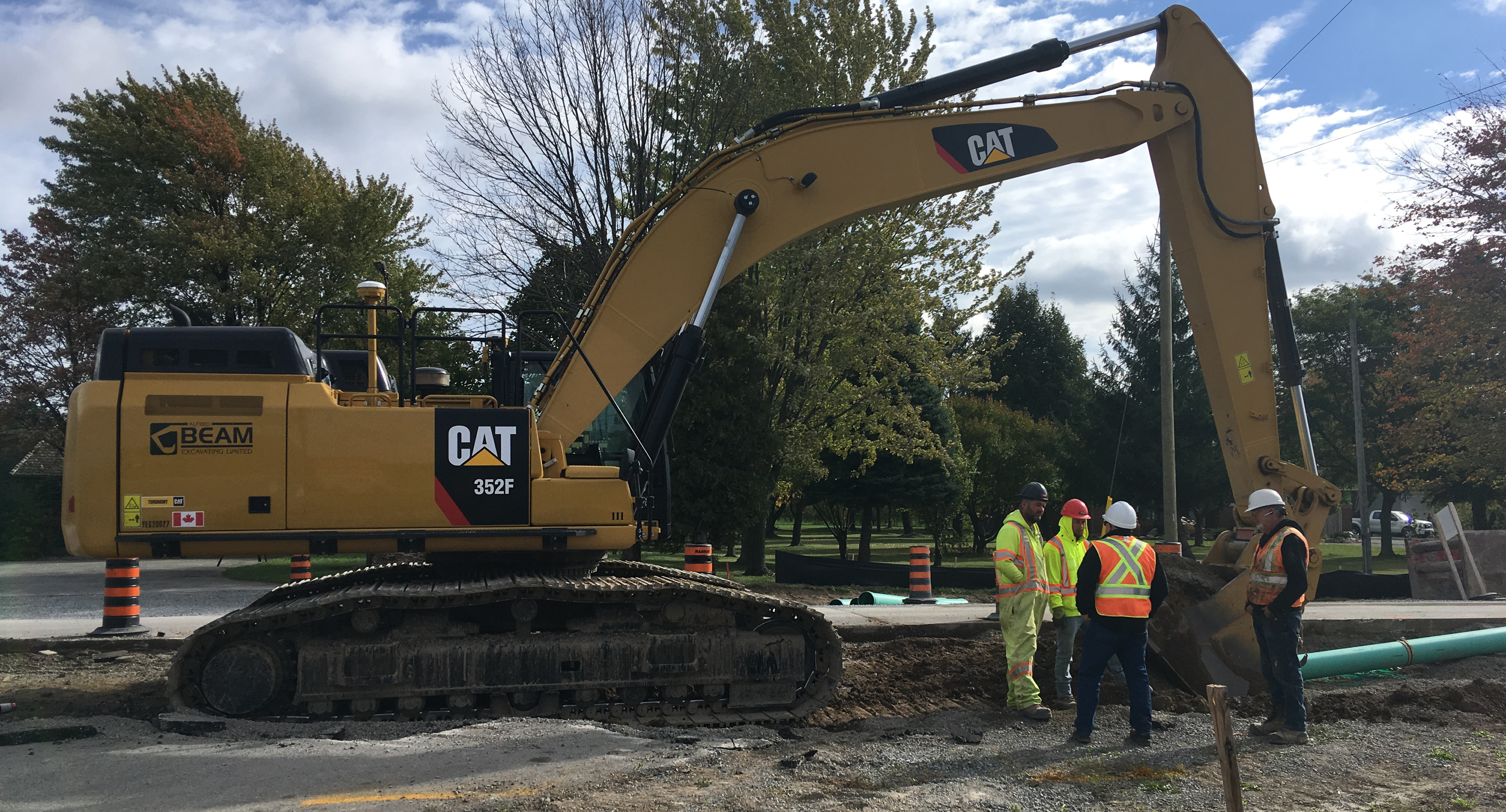 CAT Excavator with construction workers standing near it
