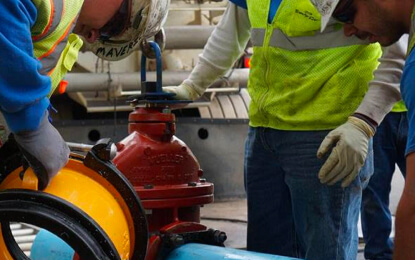Workers examining pipe equipment